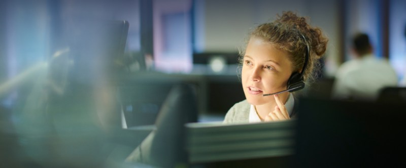 Woman speaking on a headset in a call center, engaged in conversation with a client