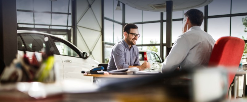Two men discussing a car purchase in a modern dealership environment