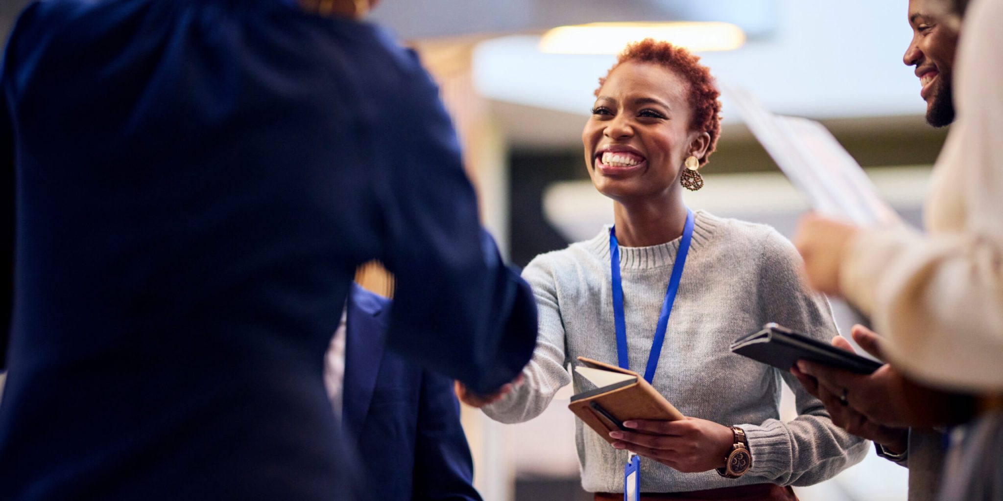 A smiling woman shakes hands with a colleague during a professional networking event