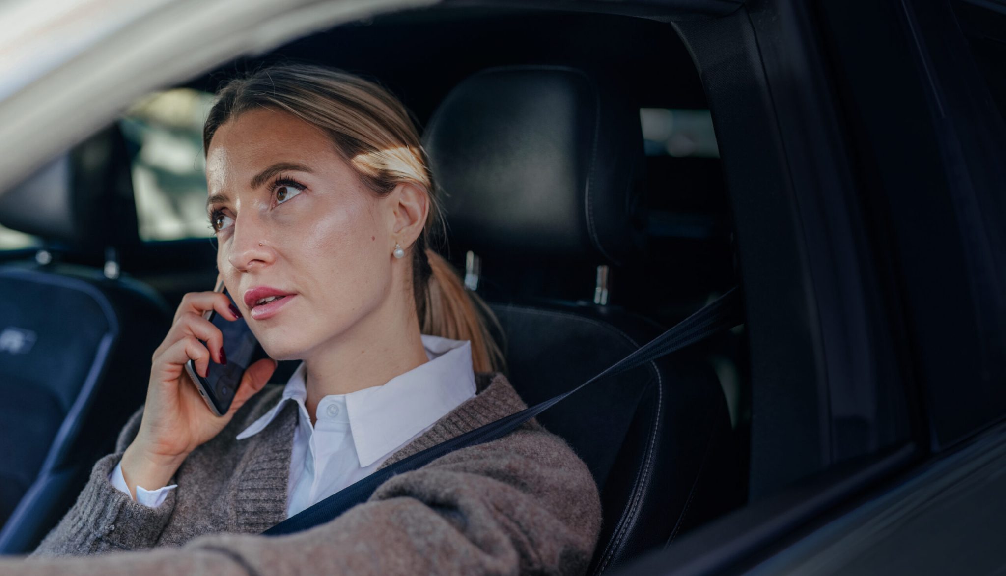 Woman in a car talking on the phone while driving, focused on the conversation