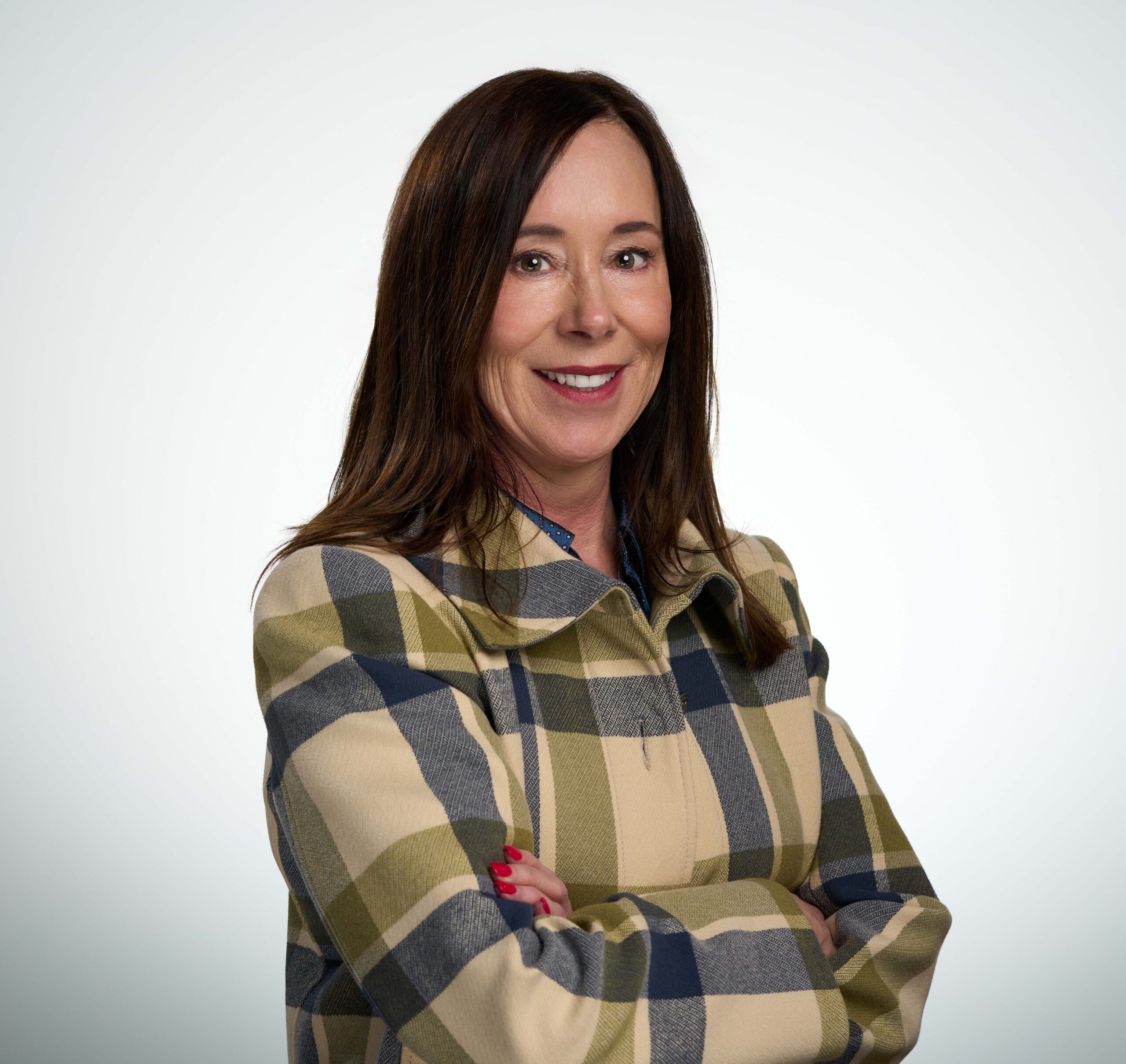 Professional woman smiling with arms crossed, set against a neutral background