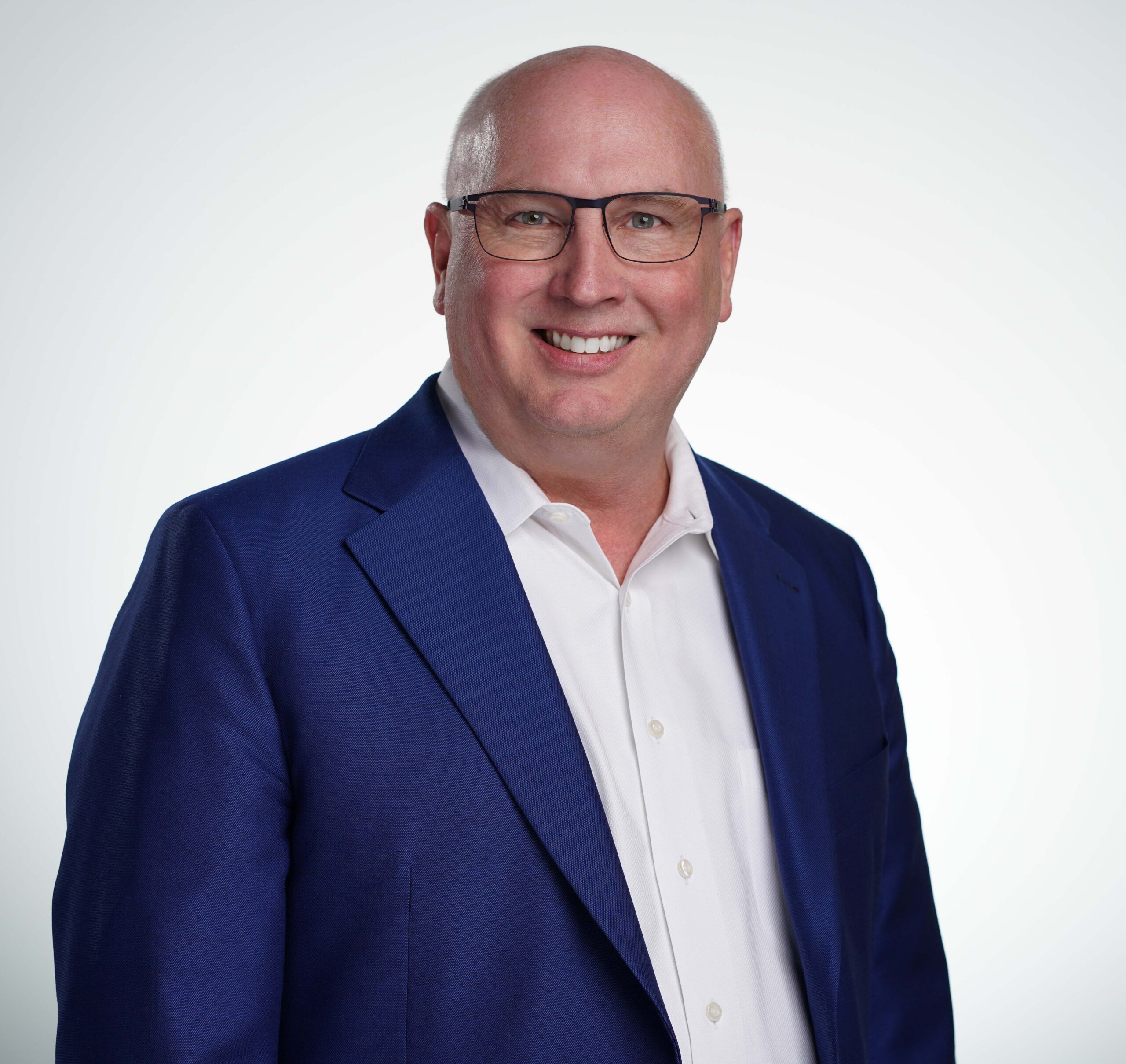 Professional headshot of a smiling man in a blue blazer, representing leadership and engagement