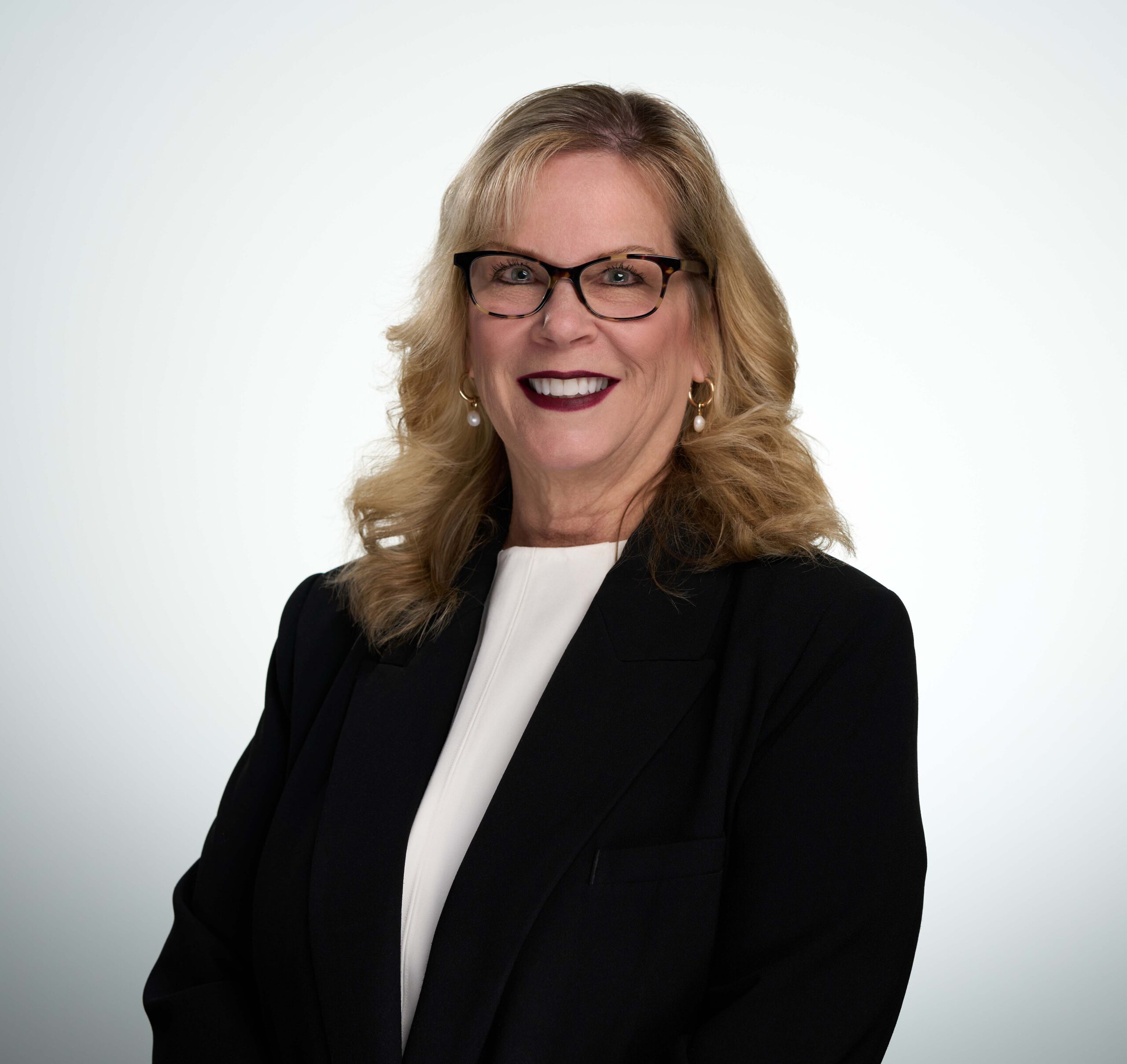 Professional portrait of a smiling woman in a black blazer, representing an approachability in a corporate setting