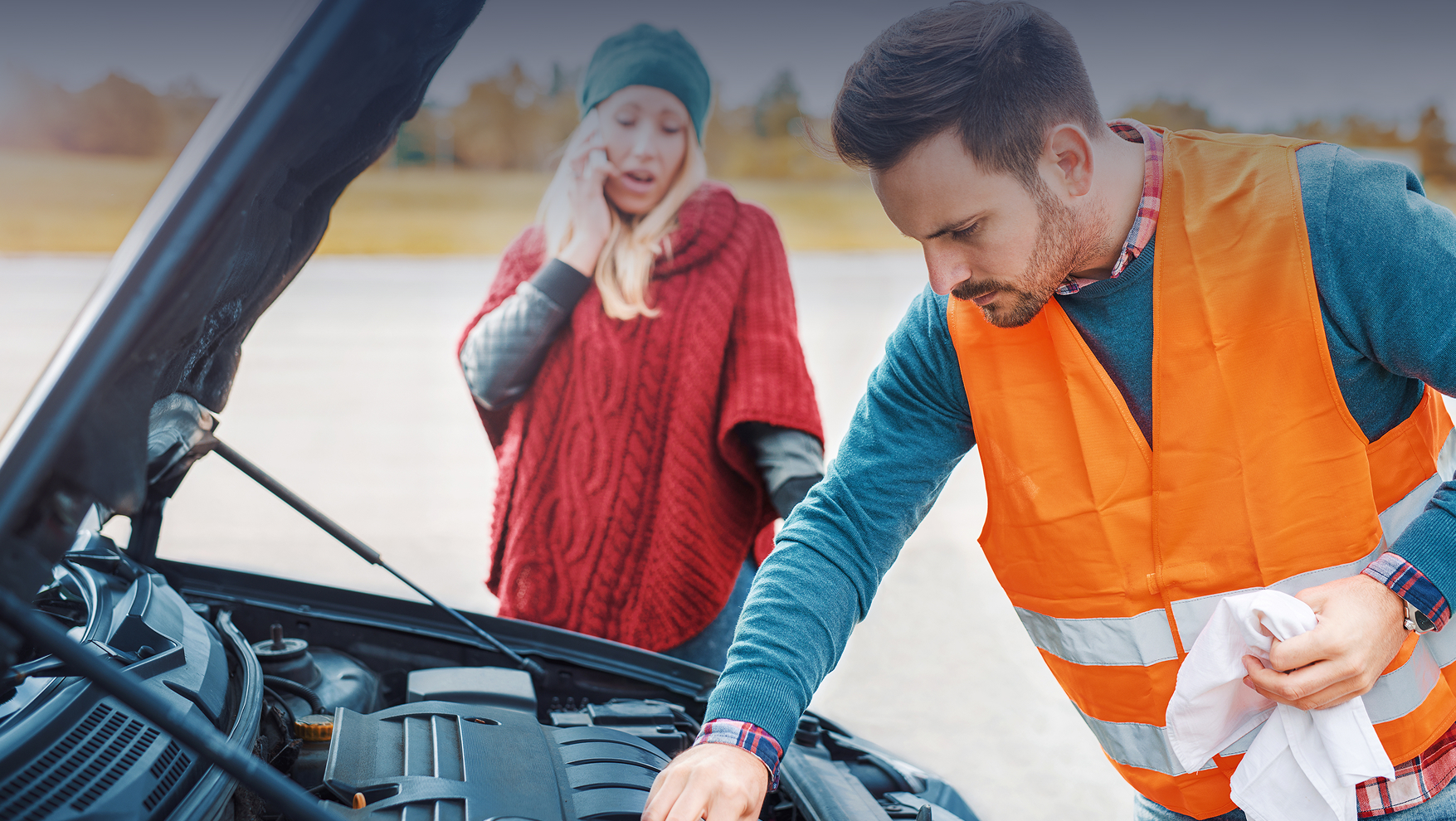 A mechanic assists a woman with her car trouble on the roadside