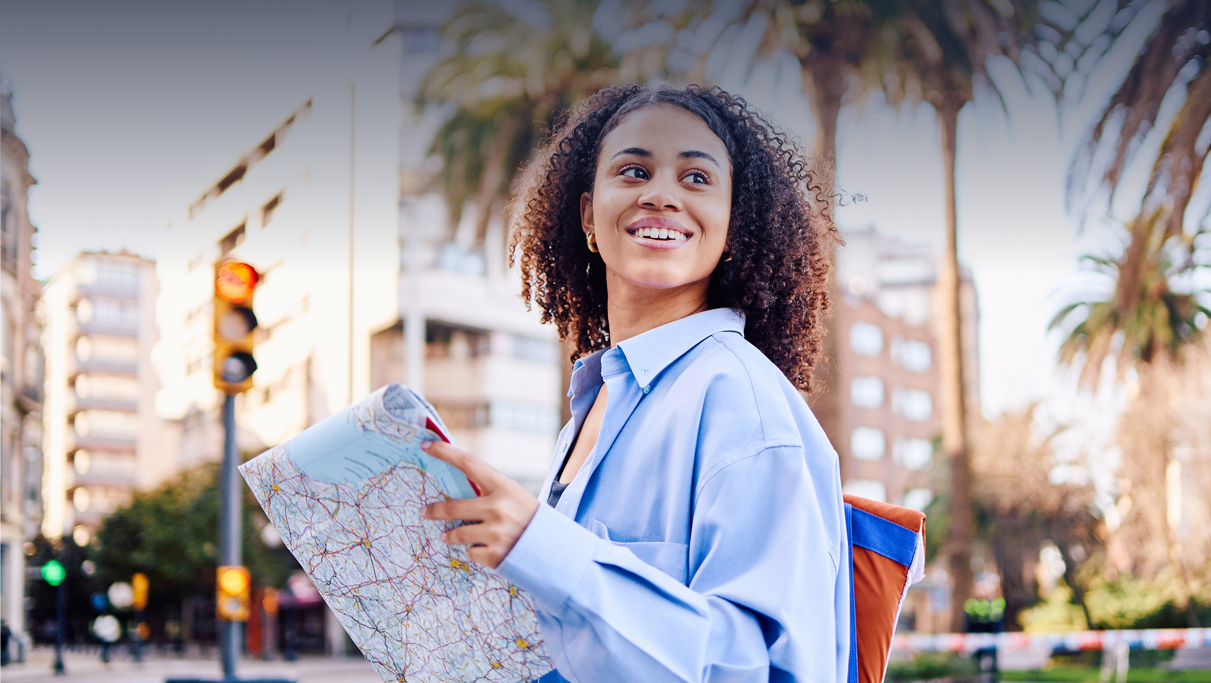 Young woman with a map smiling in a cityscape, exploring and navigating her surroundings